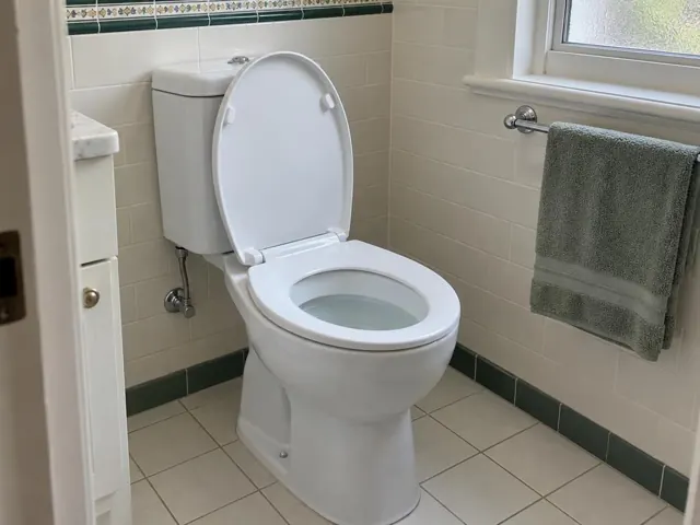 Clean white toilet in a tiled bathroom beside a window and towel rail in Fairfield