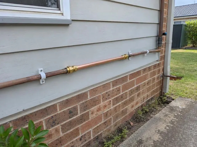 Exterior brick and weatherboard wall with a repaired copper water pipe section in Canley Vale